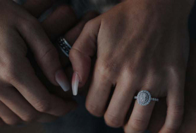 Couple holding hands showing halo engagement ring