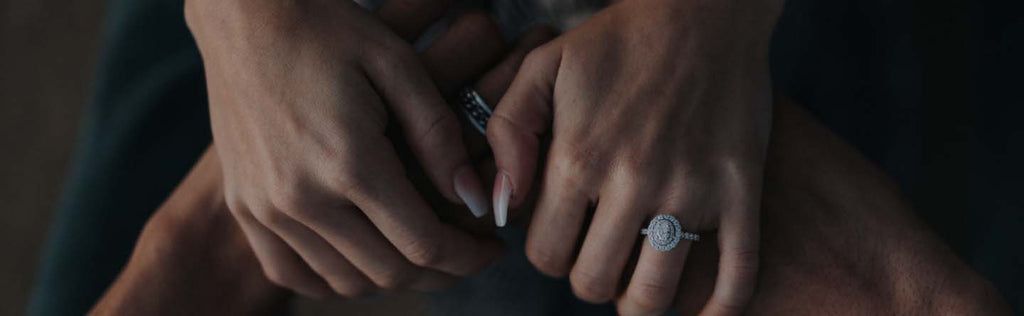 Couple holding hands showing halo engagement ring