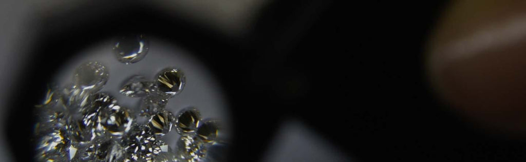 Round shaped cut diamonds through loupe on dark background