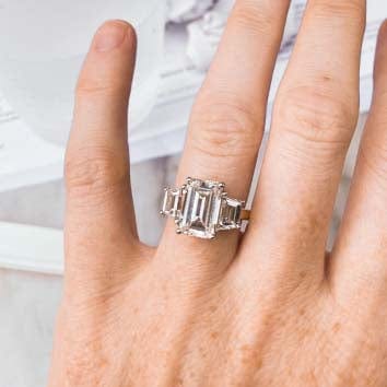 Emerald engagement ring on hand with trapezoid side stones