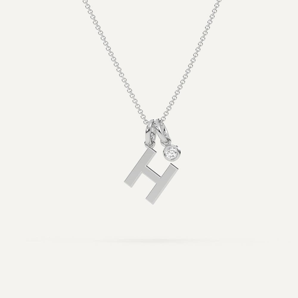 Gold initial letter H necklace adorned with sparkling diamonds on a delicate chain.