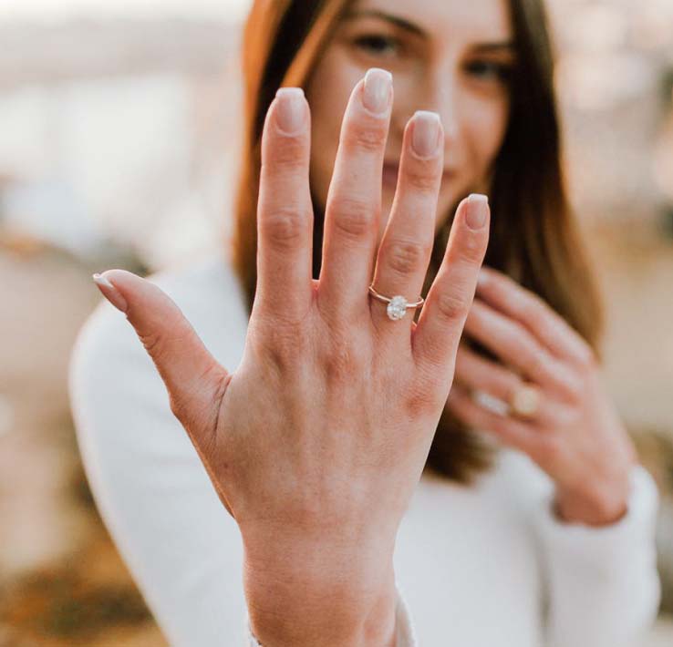 Woman showing off oval engagement ring on hand