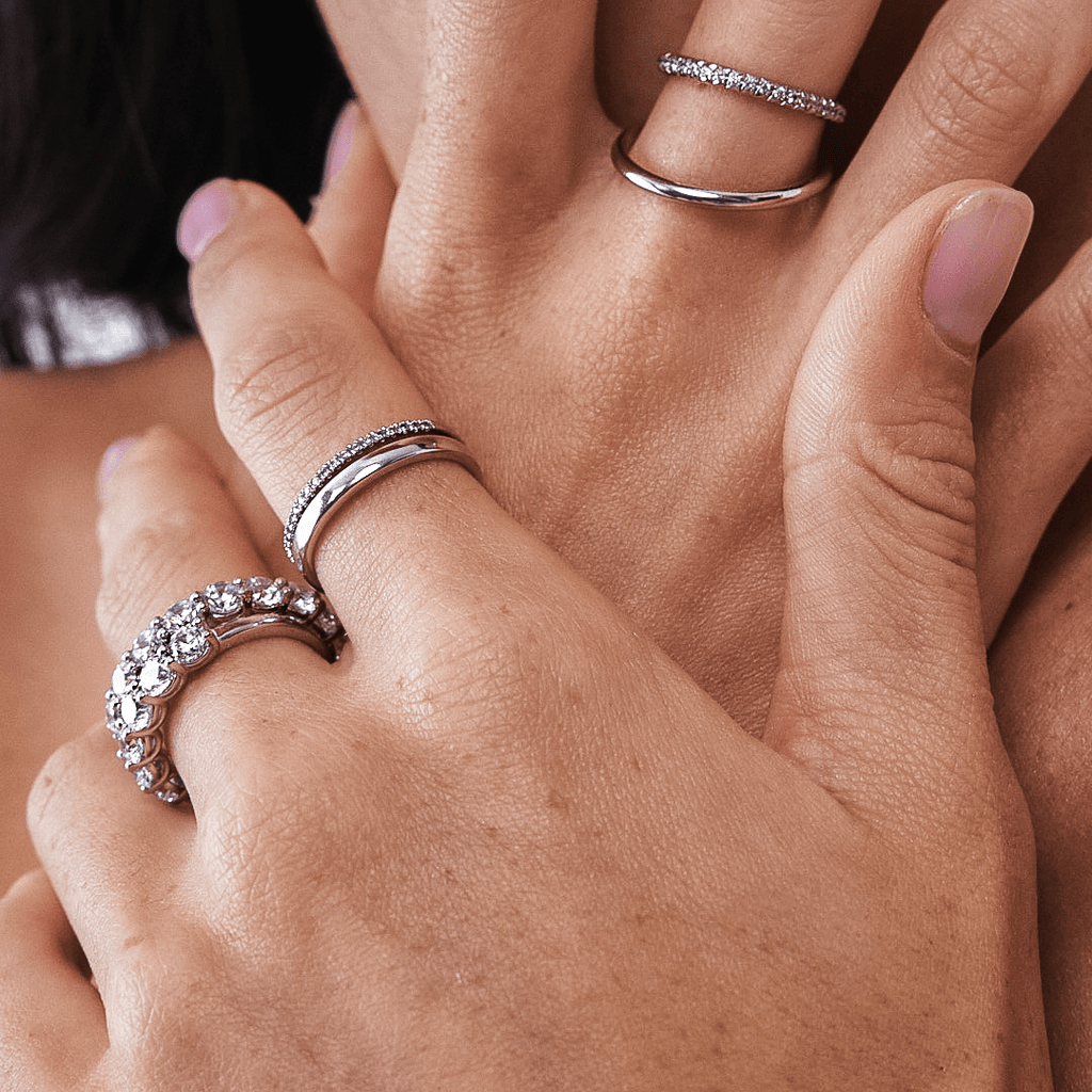Close Up of Diamond and Plain Wedding Rings on Fingers of Hand Model